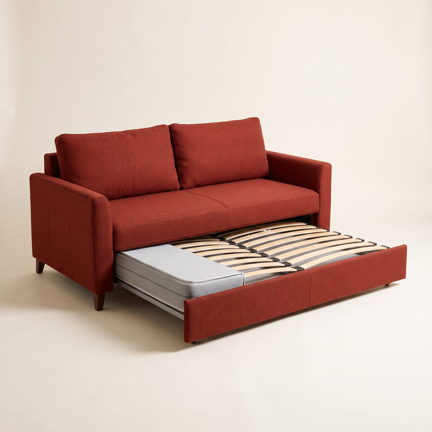 Schlafsofa in rostrotem Stoff, davor der halb ausgezogene Lattenrost mit Federleisten und Matratze.